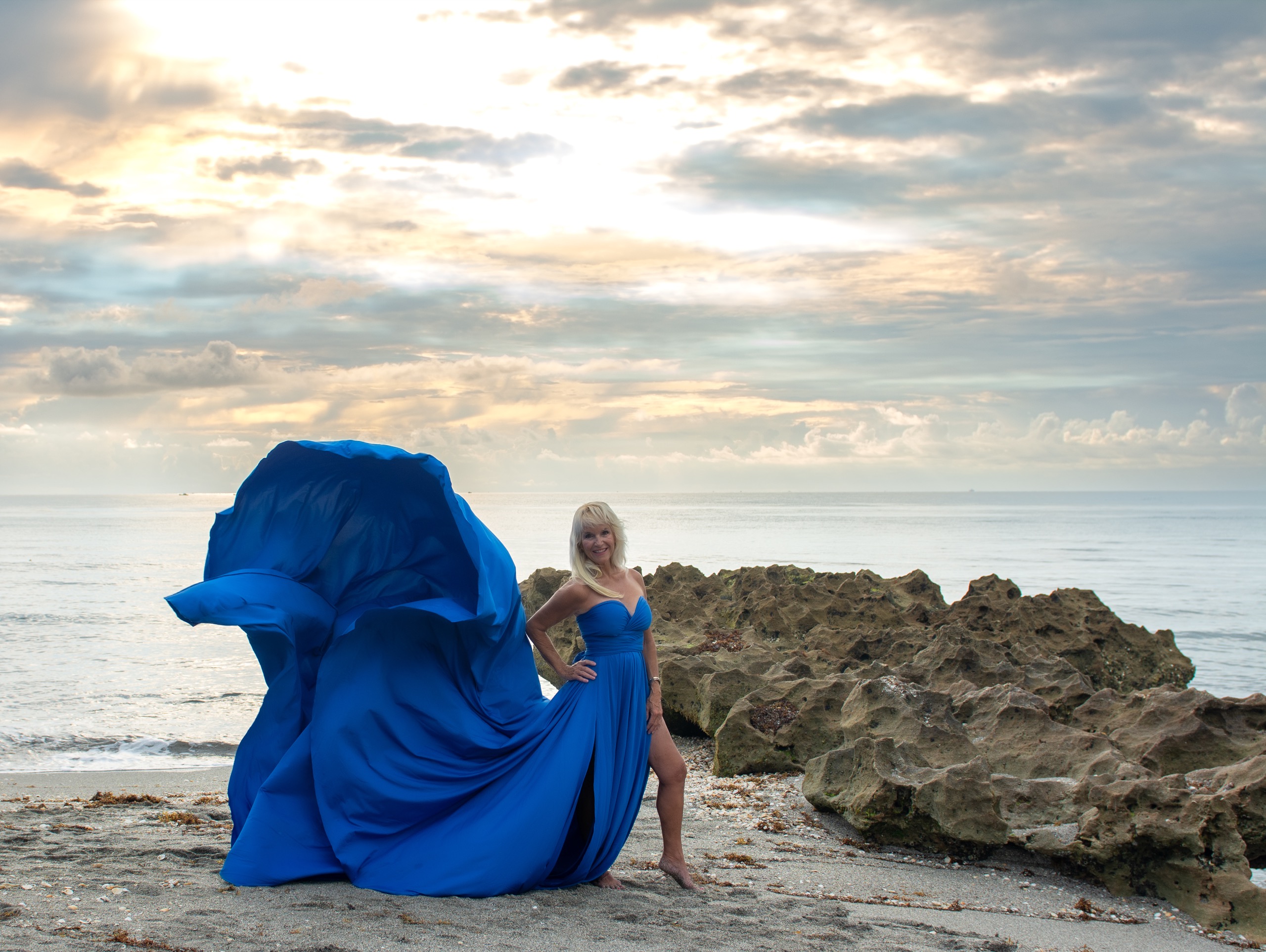 Flying dress photoshoot at sunrise on the rocks — royal blue gown