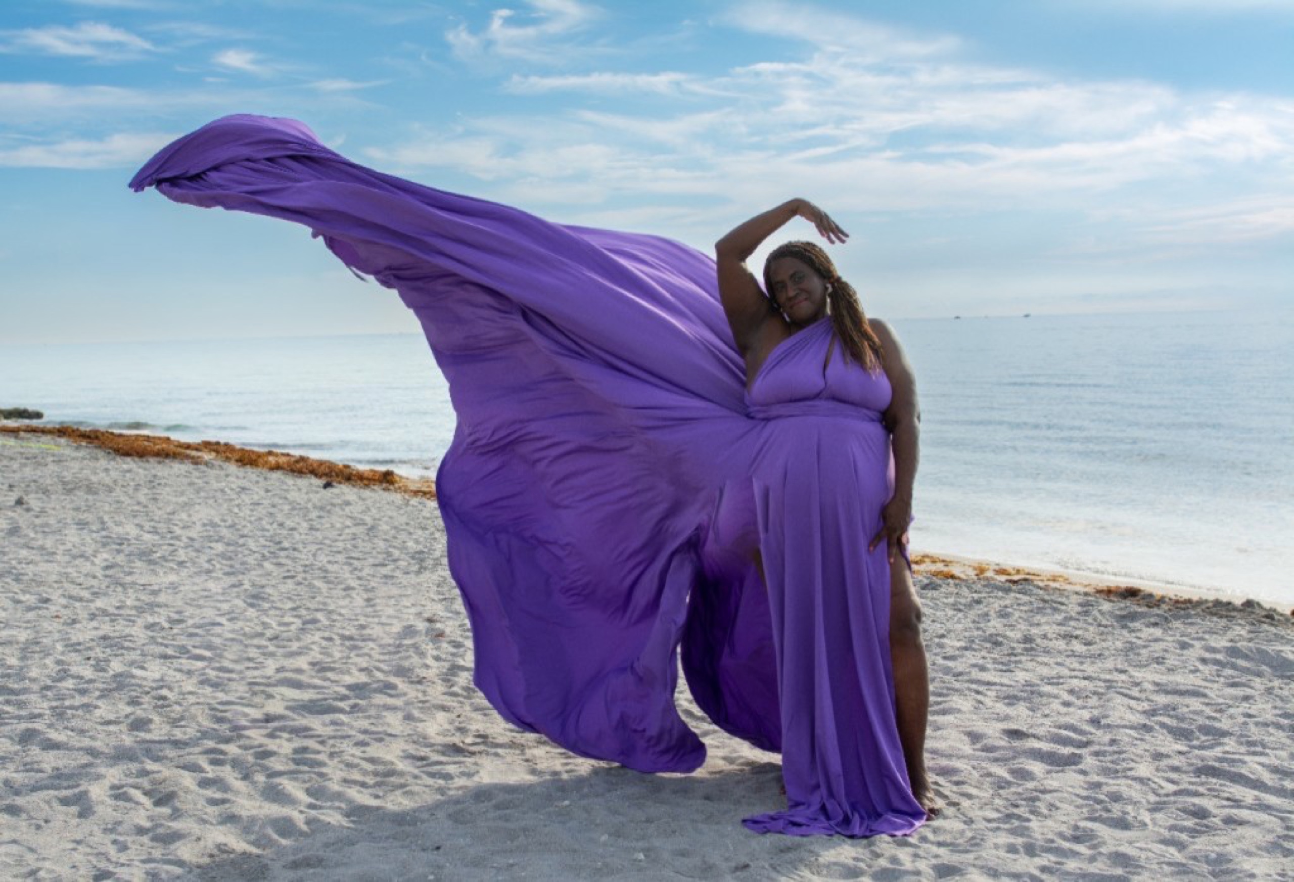 Flying dress photoshoot on the beach — purple gown billowing in the breeze